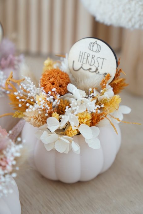 Dekorative Blütenarrangements in einer femininen Kürbisvase mit einem Schild "Herbstliebe".